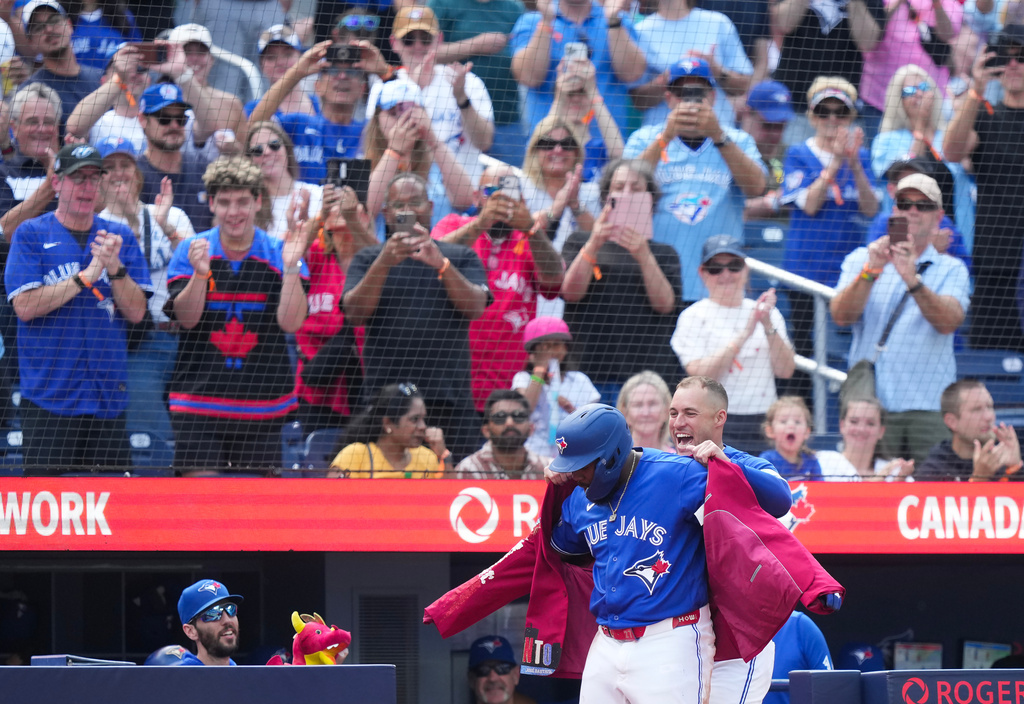 Toronto Blue Jays' Vladimir Guerrero Jr., front left, gets the home run jacket put on by teammate George Springer, front right, after hitting a solo home run against the Baltimore Orioles during the fifth inning of a baseball game in Toronto, Sunday, Sept. 13, 2026. (Nathan Denette/The Canadian Press via AP)
