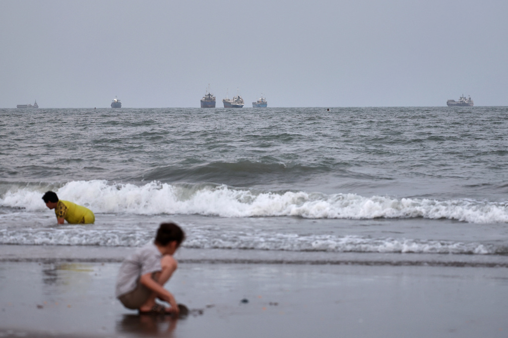 Children play at a beach as commercial vessels are anchored in the Strait of Hormuz off Bandar Abbas, Iran, Wednesday, Aug. 26, 2026. (Amir Biazar/ISNA via AP)