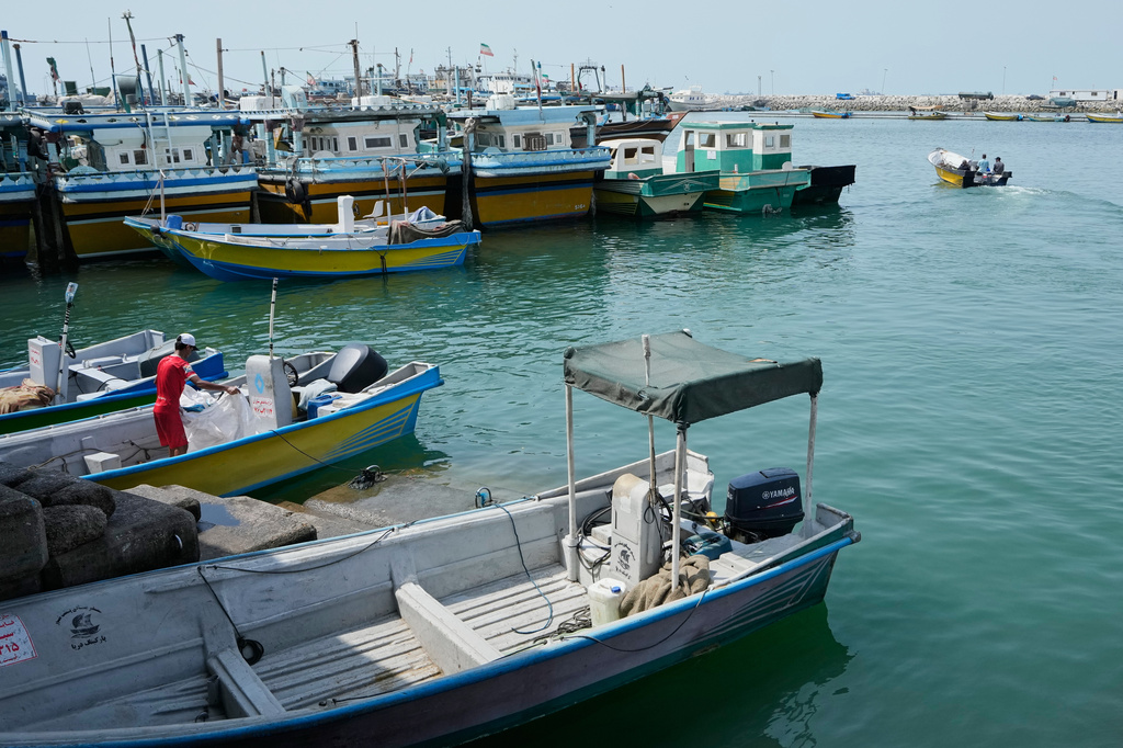 A man works aboard a boat as a motorboat leaves a harbor in Bandar Abbas, Iran, Sunday, Sept. 6, 2026. (AP Photo/Vahid Salemi)