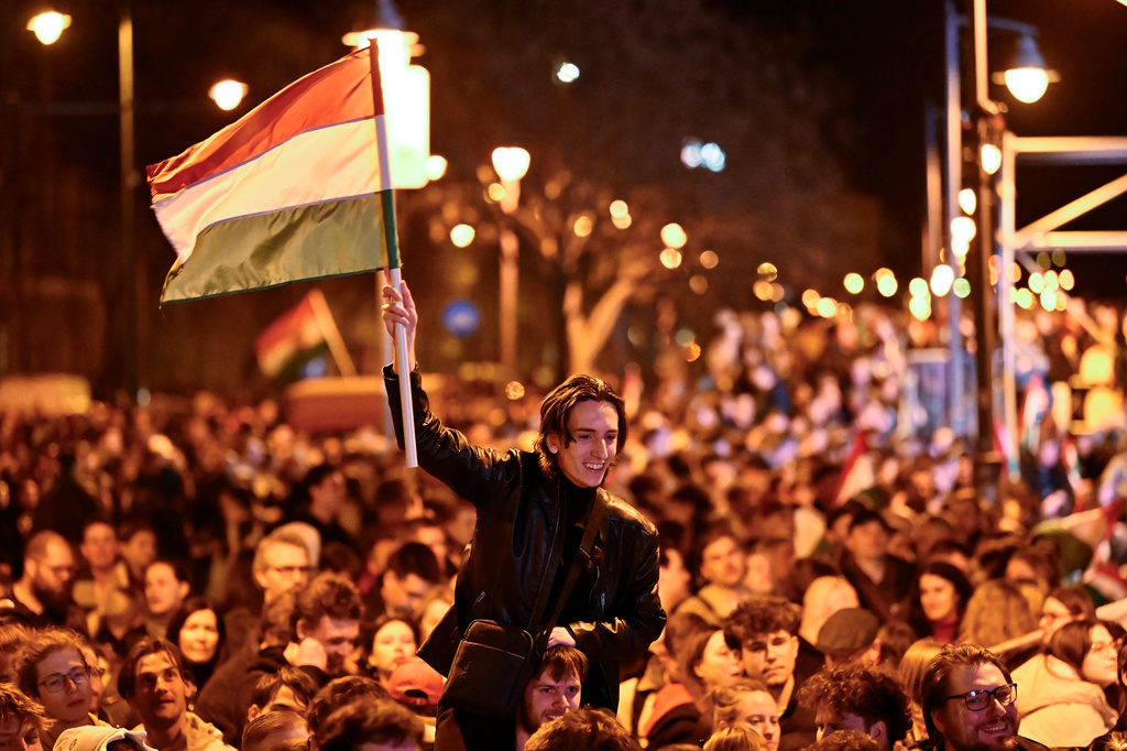 A man waves a Hungarian flag as he celebrates in the streets after the announcement of partial results of the Hungarian parliamentary in Budapest, Hungary, Sunday, April 12, 2026. (AP Photo/Denes Erdos)