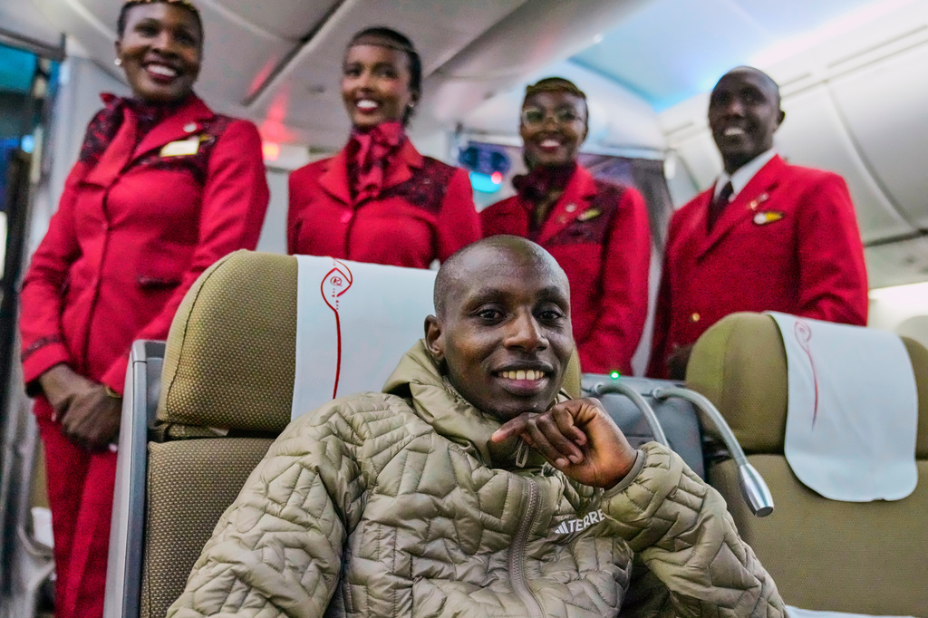 Sabastian Sawe poses with air hostesses aboard a plane from London, Wednesday, April 29, 2026, upon arrival at Jomo Kenyatta International Airport in Nairobi, Kenya, after setting a new world record in the marathon. (AP Photo/Brian Inganga) CORRECTION: Corrects spelling of first name to Sabastian, not Sebastian