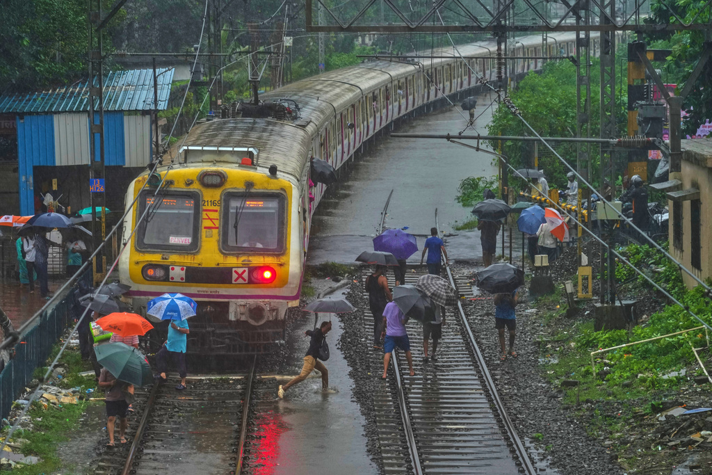 Commuters walk on waterlogged railway tracks after trains were disrupted due to heavy rainfall in Mumbai, India, Tuesday, Aug. 19, 2025. (AP Photo/ Rafiq Maqbool)