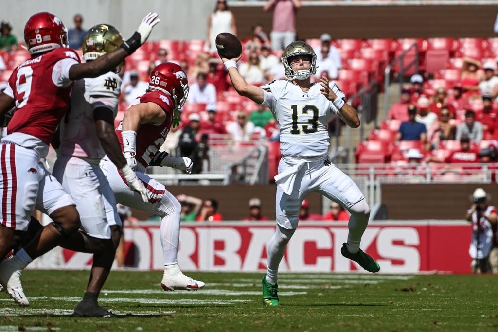 Notre Dame quarterback CJ Carr (13) throws a pass as he scrambles away from Arkansas defenders during the second half of an NCAA college football game Saturday, Sept. 27, 2025, in Fayetteville, Ark. (AP Photo/Michael Woods)