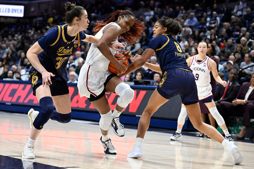 UConn guard Blanca Quinonez splits between the defense of Notre Dame forward Gisela Sanchez (30) and guard Cassandre Prosper (8) in the first half of an NCAA college basketball game, Monday, Jan. 19, 2026, in Storrs, Conn. (AP Photo/Jessica Hill)