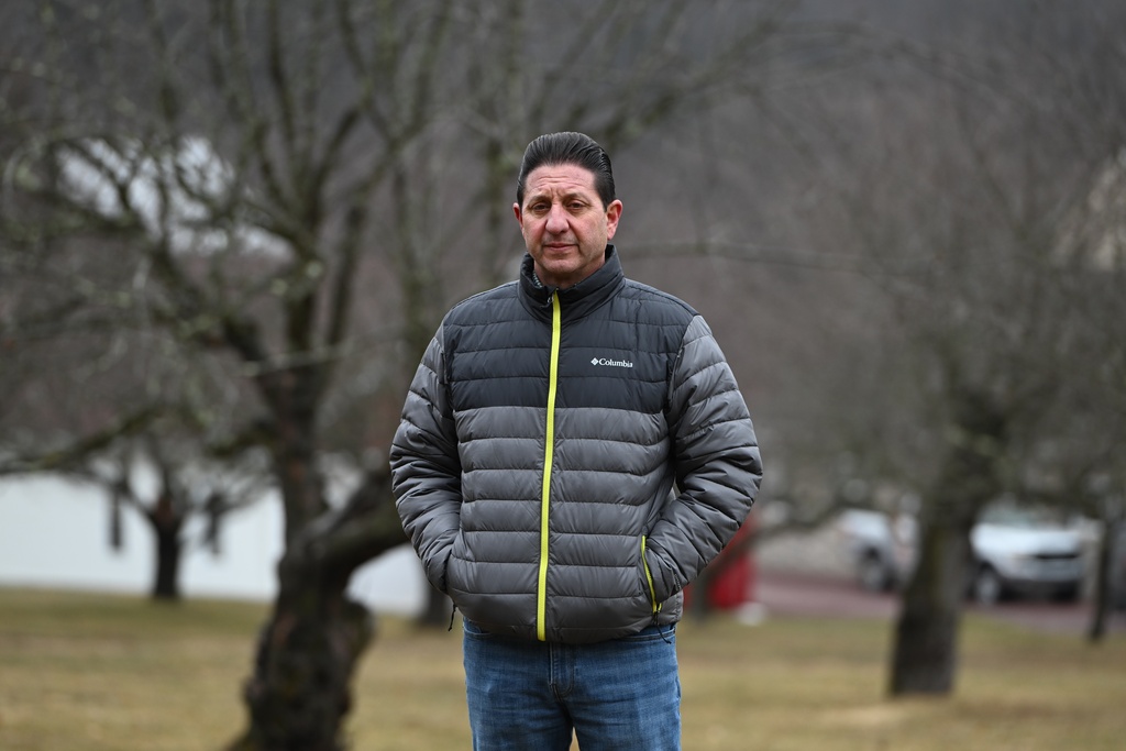 John Zola stands in an apple tree grove on his property on a spot where he says the local electric utility wants to build a 500-kilovolt line across his land, March 4, 2026, in Sugarloaf, Pa. (AP Photo/Marc Levy)