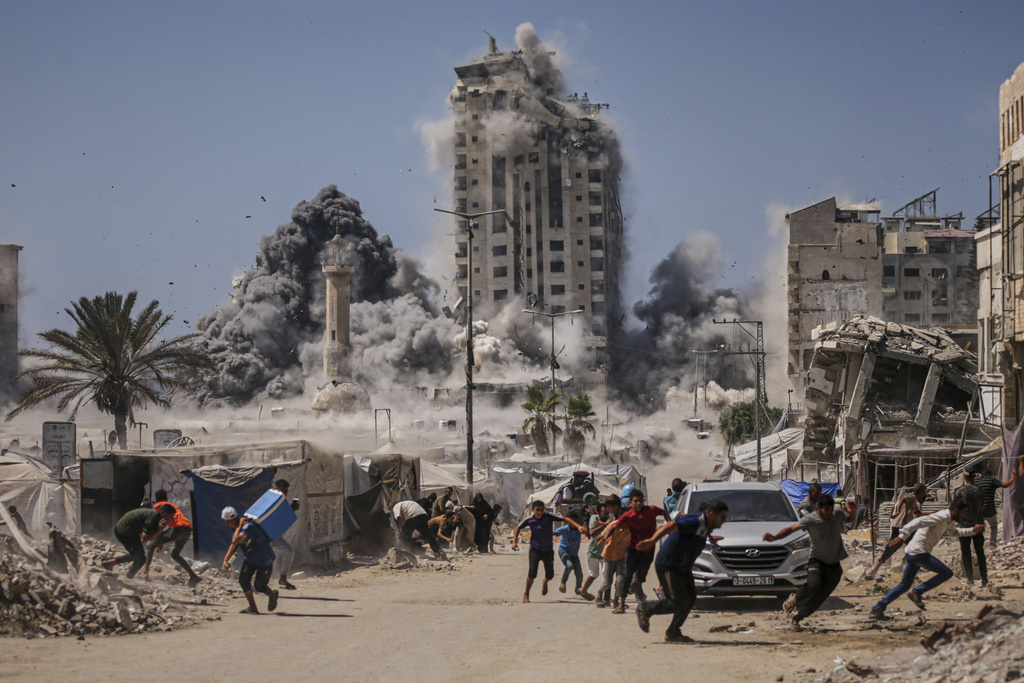 Palestinians run for cover during an Israeli airstrike on a high-rise building in Gaza City, Friday, Sept. 5, 2025, after the Israeli army issued a prior warning. (AP Photo/Yousef Al Zanoun)