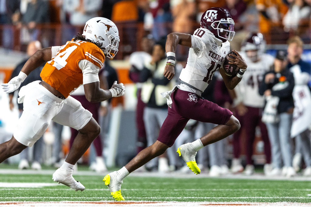Texas A&M quarterback Marcel Reed (10) scrambles away from Texas defensive end Brad Spence, left, during the first half of an NCAA college football game, Friday, Nov. 28, 2025, in Austin, Texas. (AP Photo/Stephen Spillman)