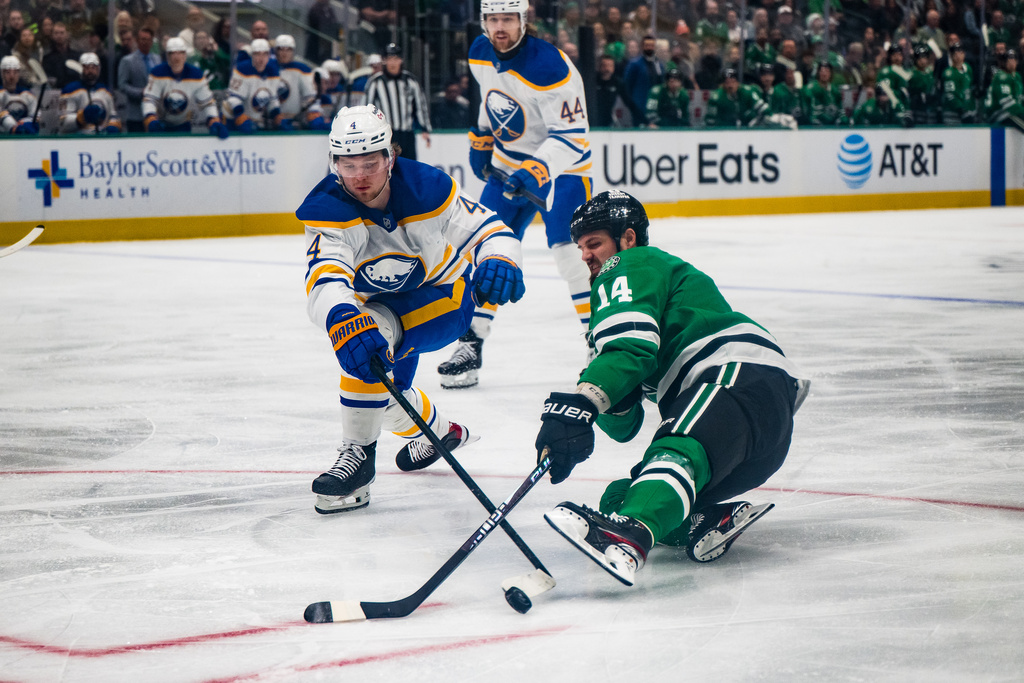 Dallas Stars left wing Jamie Benn (14) slides towards the puck as Buffalo Sabres defenseman Bowen Byram (4) follows during an NHL hockey game, Wednesday, Dec. 31, 2025, Dallas. (AP Photo/Jessica Tobias)