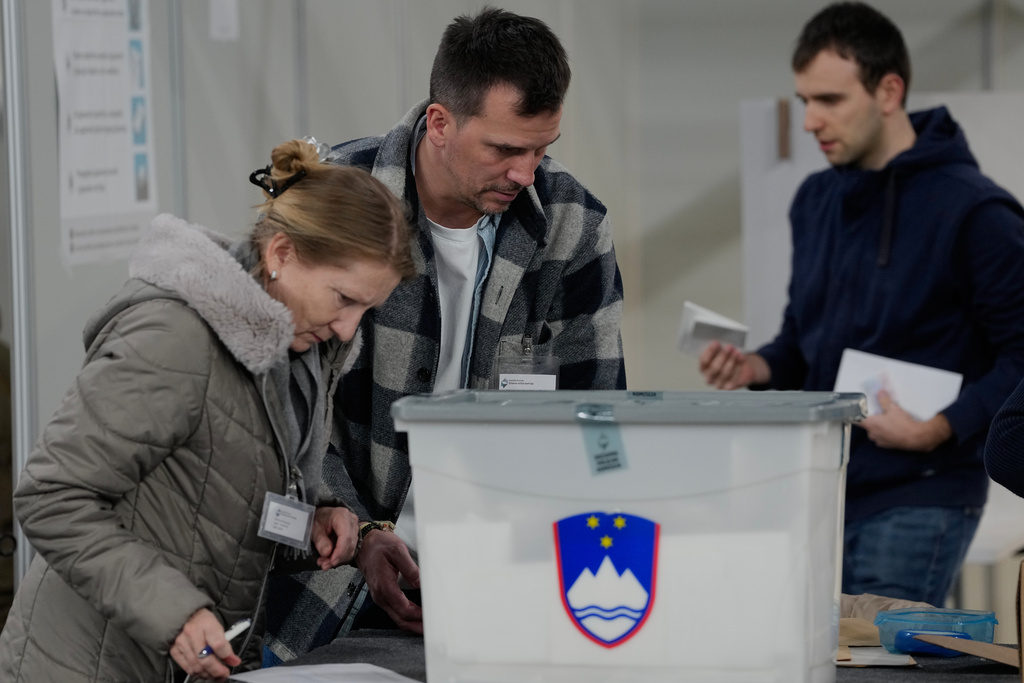 Members of the electoral commission handle ballots at a sports hall turned polling station for early vote in Ljubljana, Slovenia, Wednesday, March 18, 2026. (AP Photo/Darko Bandic)