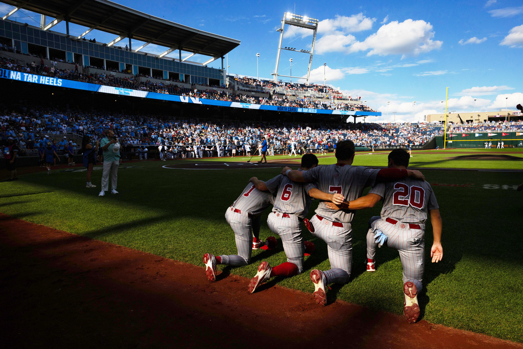 Oklahoma's Jason Walk (1), Kyle Branch (6), Jaxon Willits (7) and Trey Gambill (20) kneel together before playing against North Carolina in Game 3 of the NCAA College World Series baseball finals in Omaha, Neb., Monday, June 22, 2026. (AP Photo/Rebecca S. Gratz)