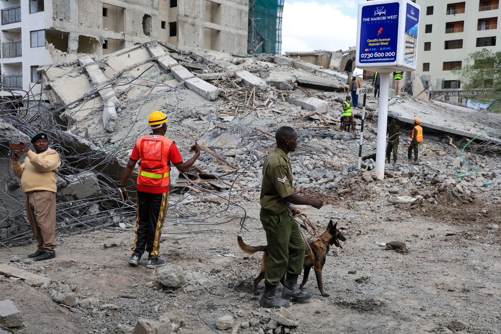 A police officer with a sniffer dog searches for survivors following the collapse of a building in Nairobi, Kenya, Friday, Jan. 2, 2026. (AP Photo/Andrew Kasuku)