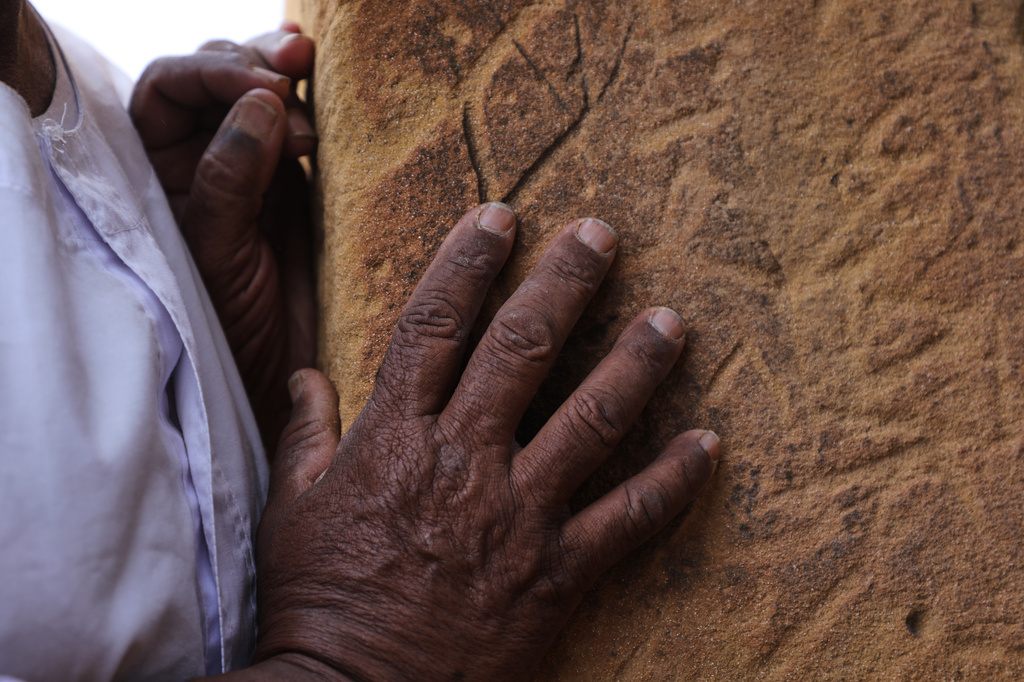 A visitor runs their hand along the stone blocks of a pyramid at the Meroe archaeological site in Bejrawiya, Sudan, Sunday, Aug. 2, 2026. (AP Photo/Mohnd Blal)