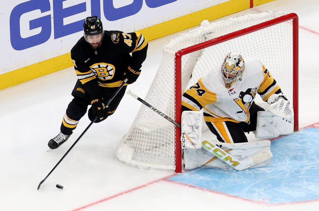 Boston Bruins center Mark Kastelic maneuvers the puck around the net guarded by Pittsburgh Penguins goaltender Stuart Skinner (74) during the second period of an NHL hockey game, Sunday, Jan. 11, 2026, in Boston. (AP Photo/Mark Stockwell)
