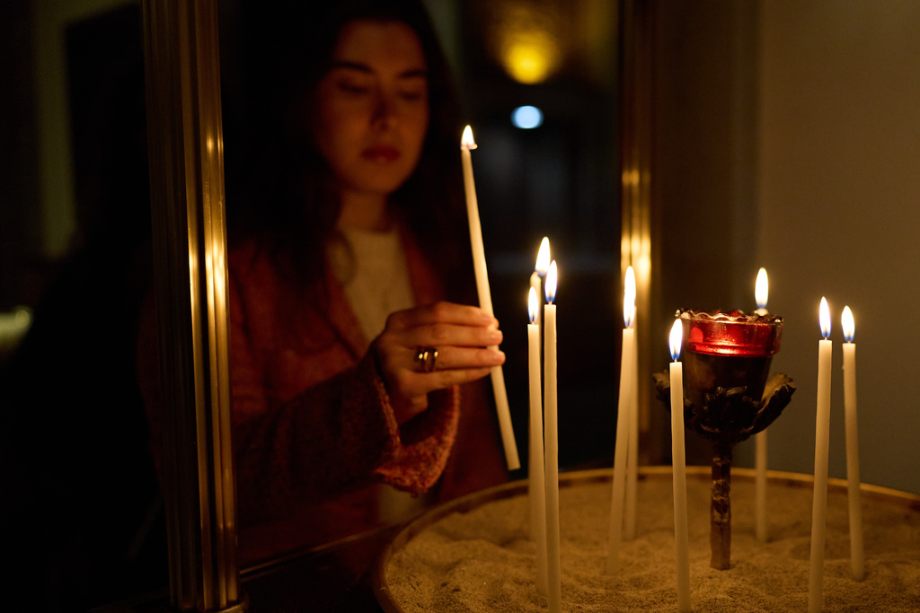 A person lights a candle during service at St. Sophia Greek Orthodox Cathedral Tuesday, Nov. 18, 2025, in Los Angeles. (AP Photo/Allison Dinner)