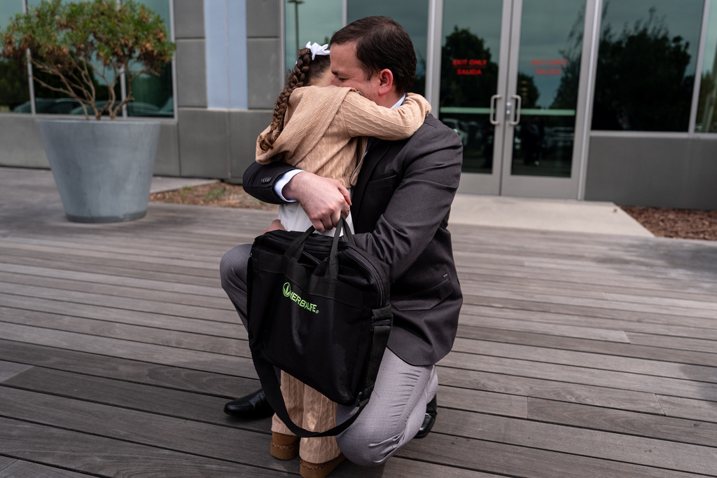 FILE - Milenko Faria, whose wife, Dr. Rubeliz Bolivar, is in immigration custody, hugs their daughter, Milena, after his asylum interview at the U.S. Citizenship and Immigration Services facility in Tustin, Calif., Thursday, April 16, 2026. (AP Photo/Jae C. Hong, File)