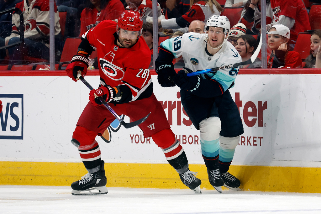 Carolina Hurricanes' William Carrier (28) clears the puck from Seattle Kraken's Ben Meyers (59) during the second period of an NHL hockey game in Raleigh, N.C., Saturday, Jan. 10, 2026. (AP Photo/Karl DeBlaker)