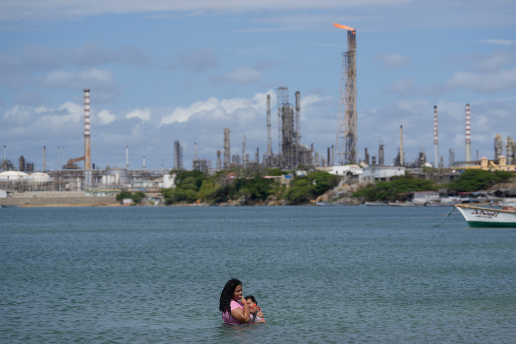 Ceylis Mendez and her daughter Zoe cool off in the Gulf of Venezuela in front of the Cardon oil refinery off the shore of Punta Cardon, Venezuela, Wednesday, Jan. 14, 2026. (AP Photo/Matias Delacroix)