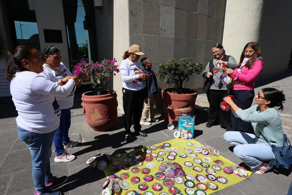 People whose relatives have gone missing decorate Christmas ornaments with photographs of their missing loved ones to hang on the Tree of Hope during an event organized by the diocese of Ecatepec at the Church of the Sacred Heart of San Cristobal in Ecatepec, State of Mexico, Monday, Nov. 17, 2025. (AP Photo/Ginnette Riquelme)