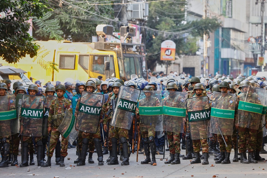 Army soldiers in riot gear stand guard as protesters shout slogans outside the demolished residence of Sheikh Mujibur Rahman, Bangladesh's former leader and the father of the country's ousted Prime Minister Sheikh Hasina following the verdict against her, in Dhaka, Bangladesh, Monday, Nov. 17, 2025. (AP Photo/ Rajib Dhar)