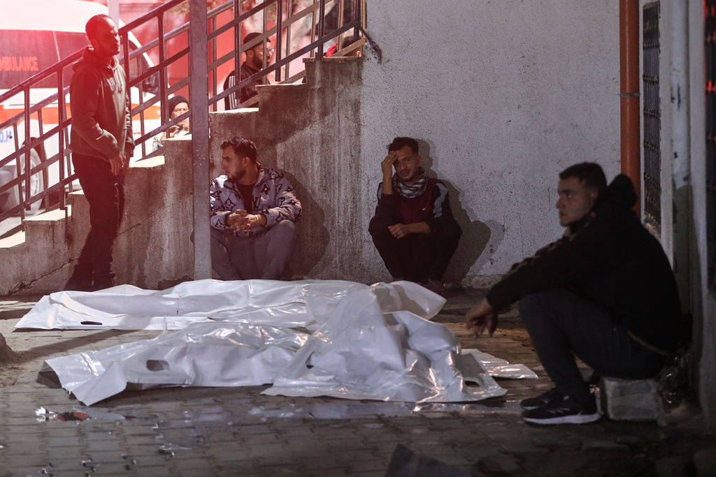 Palestinians mourn next to the bodies of people killed in an Israeli military strike, after arriving at Shifa Hospital in Gaza City, Friday, Dec. 19, 2025. (AP Photo/Yousef Al Zanoun)