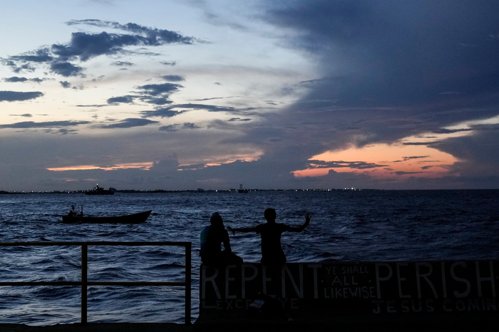 FILE - People sit on the seawall as the sun sets in Georgetown, Guyana, Tuesday, Nov. 19, 2024. (AP Photo/Matias Delacroix, File)