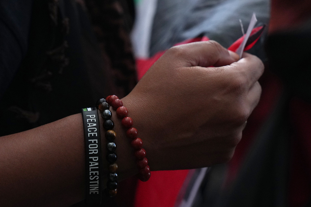 A students wears a bracelet showing support for Palestinians as she takes part in a demonstration with protesters holding banners, placards and flags during an Inter-university march for Gaza in London, Tuesday, Oct. 7, 2025. (AP Photo/Joanna Chan)