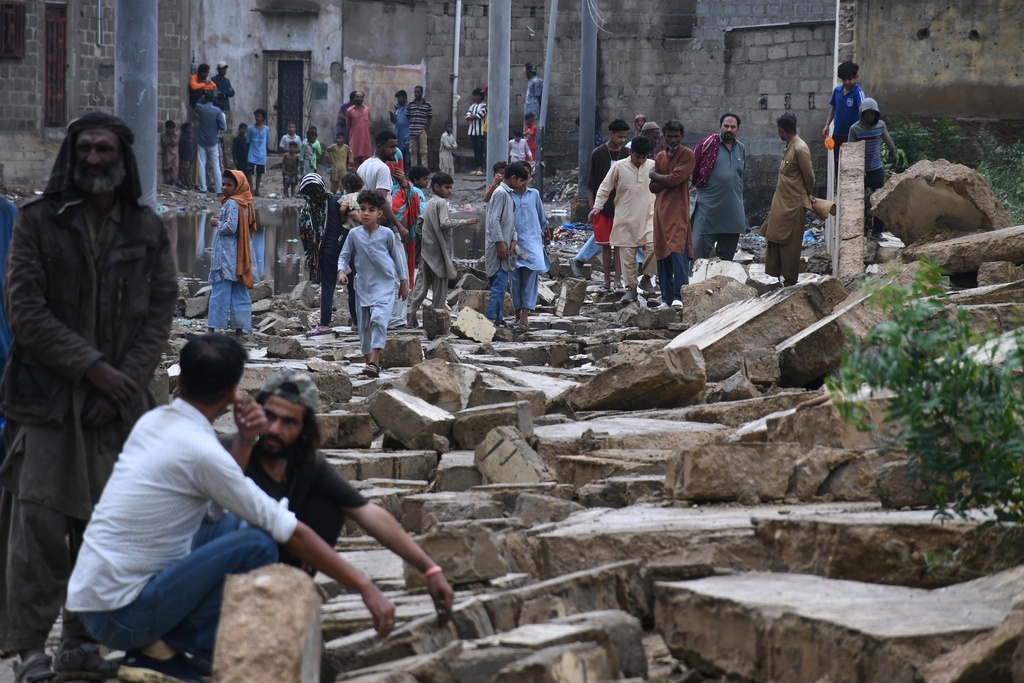 Local residents navigate through the rubble of boundary wall collapsed due to heavy rains and strong winds in Karachi, Pakistan, Thursday, March 19, 2026. (AP Photo/Ali Raza)