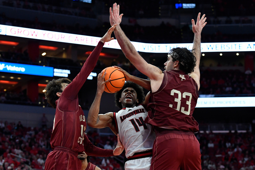Louisville guard Adrian Wooley (14) attempts a shot through Boston College guard Luka Toews (10), left, and center Boden Kapke (33) during the second half of an NCAA college basketball game in Louisville, Ky., Saturday, Jan. 10, 2026. (AP Photo/Timothy D. Easley)