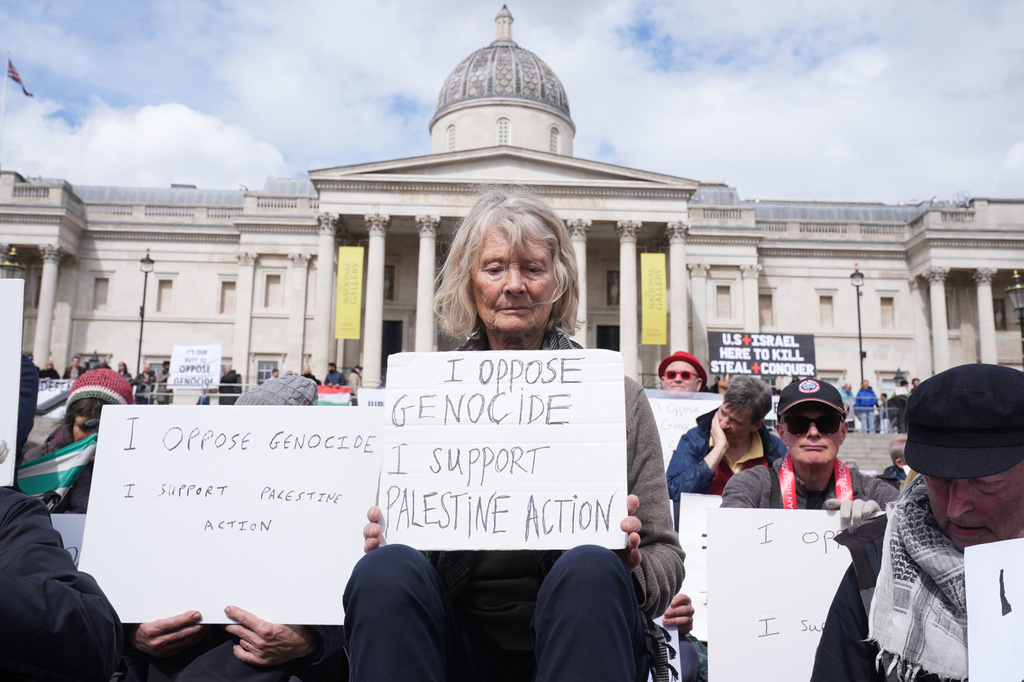 Protesters hold up placards at a demonstration against the ban on Palestine Action, in Trafalgar Square, central London, Saturday April 11, 2026. (Lucy North/PA via AP)
