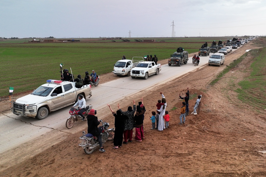 Local residents, predominantly Arab, welcome a convoy of Syria's Interior Ministry forces as it passes through en route to the mostly Kurdish town of Qamishli, where the forces are deploying under a ceasefire agreement with the Kurdish-led Syrian Democratic Forces (SDF), near the village of Mazraat al-Nahar, northeastern Syria, Tuesday, Feb. 3, 2026. (AP Photo/Ghaith Alsayed)