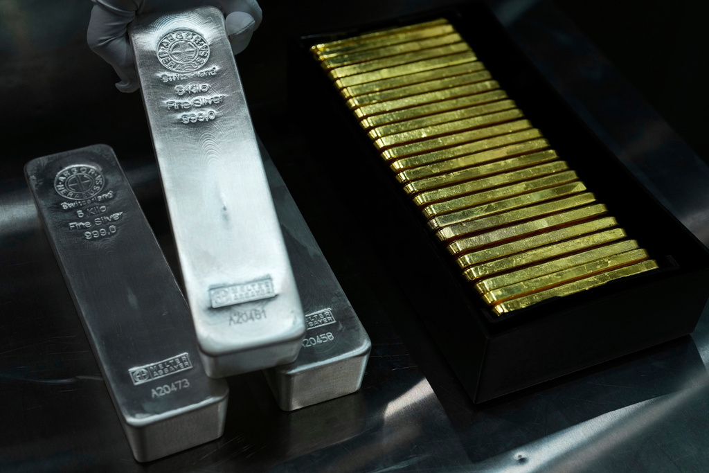 FILE - An employee of Pro Aurum gold house lifts 1 Kg silver bars of 999.9 purity besides 1 Kg gold bars in the safe deposit boxes room in Munich, Germany, Friday, April 25, 2025. (AP Photo/Matthias Schrader, File)