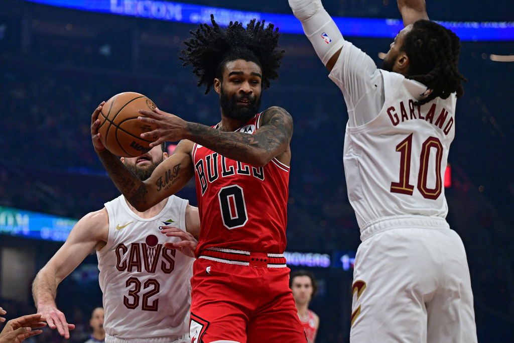 Chicago Bulls guard Coby White goes to the basket between Cleveland Cavaliers guard Darius Garland, right, and forward Dean Wade in the first half of an NBA basketball game, Friday, Dec. 19, 2025, in Cleveland. (AP Photo/David Dermer)