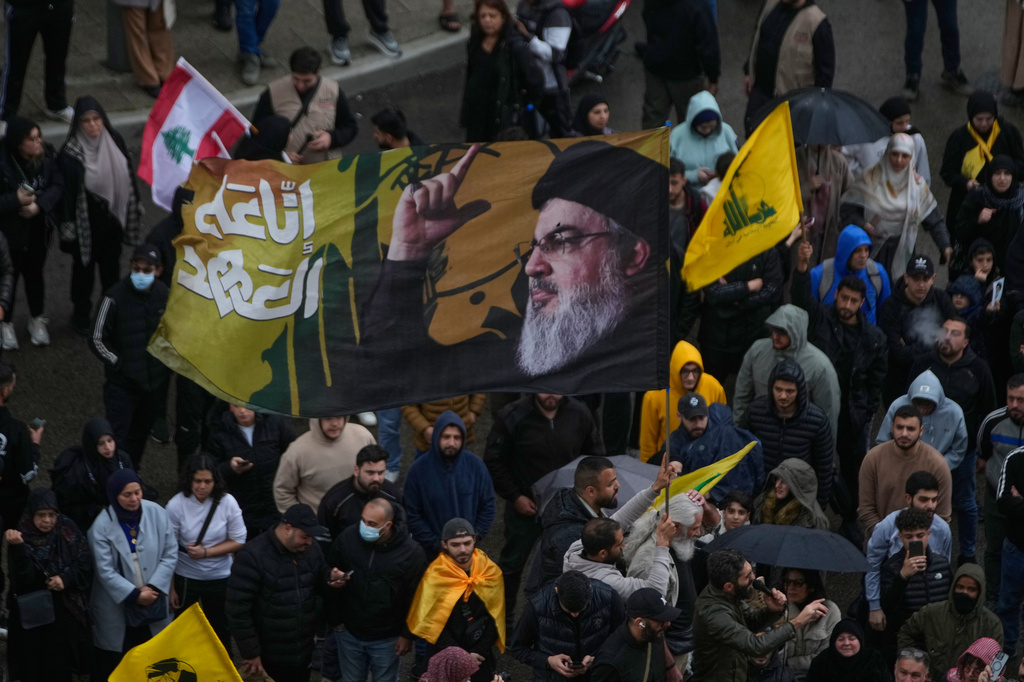 A Hezbollah supporter waves a flag with the portrait of the late Hezbollah leader Sayyed Hassan Nasrallah during a protest against the Lebanese Prime Minister Nawaf Salam, in front the government palace in Beirut, Lebanon, Friday, April 10, 2026. (AP Photo/Hussein Malla)