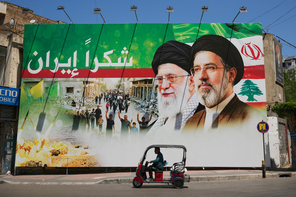 A man rides a scooter past a giant billboard that shows the late Iranian leader Ayatollah Ali Khamenei, center, and Iranian Supreme Leader Ayatollah Mojtaba Khamenei, with Arabic writing that reads: "Thank you Iran", in Dahiyeh, Beirut's southern suburbs, Lebanon, Monday, June 15, 2026. (AP Photo/Hussein Malla)