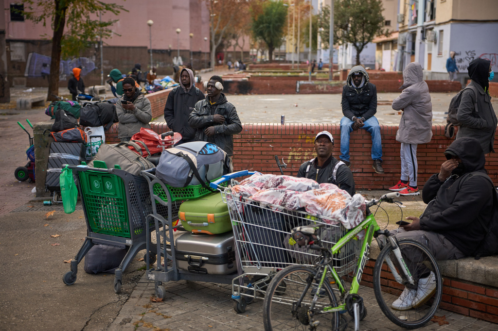 FILE - Migrants sit together with their belongings after being evicted by police from an abandoned school where they had been living in Badalona, near Barcelona, Spain, Wednesday, Dec. 17, 2025. (AP Photo/Emilio Morenatti, File)
