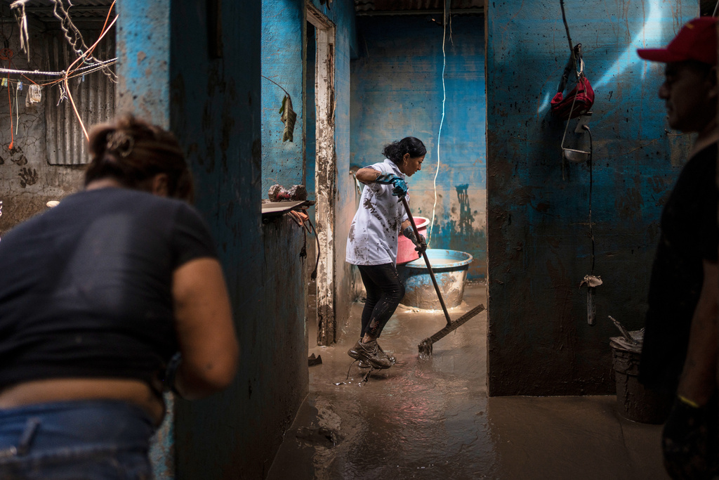 People clean the Olvera Gomez family's house in Poza Rica, Veracruz state, Mexico, Monday, Oct. 13, 2025, after torrential rains. (AP Photo/Felix Marquez)