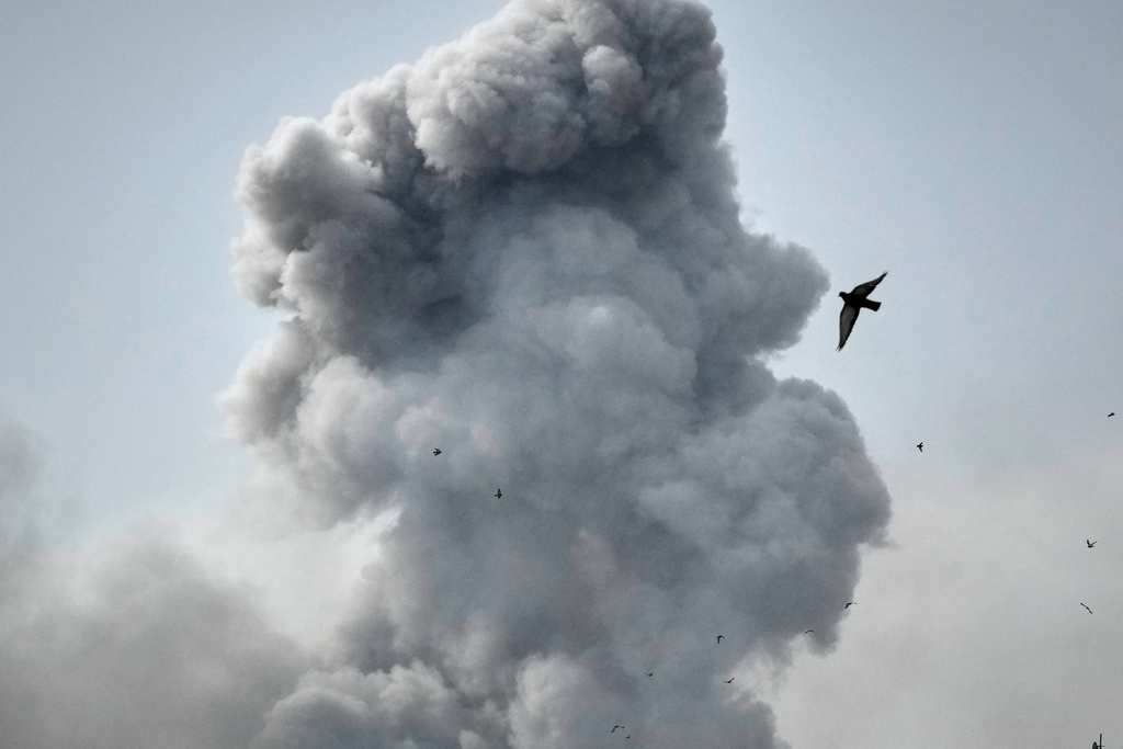 A bird flies by a plume of smoke rising after a strike in Tehran, Iran, Monday, March 2, 2026. (AP Photo/Vahid Salemi)
