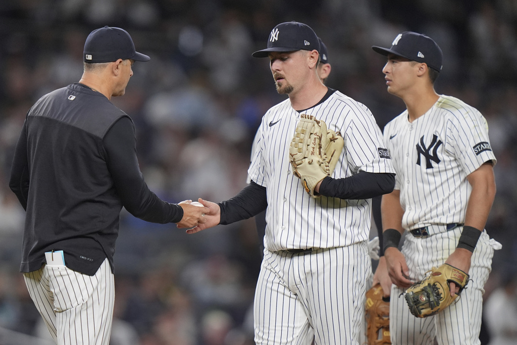 New York Yankees pitcher Mark Leiter Jr., center, hands the ball to manager Aaron Boone, left, as Anthony Volpe watches during the seventh inning of a baseball game against the Detroit Tigers Tuesday, Sept. 9, 2025, in New York. (AP Photo/Frank Franklin II)