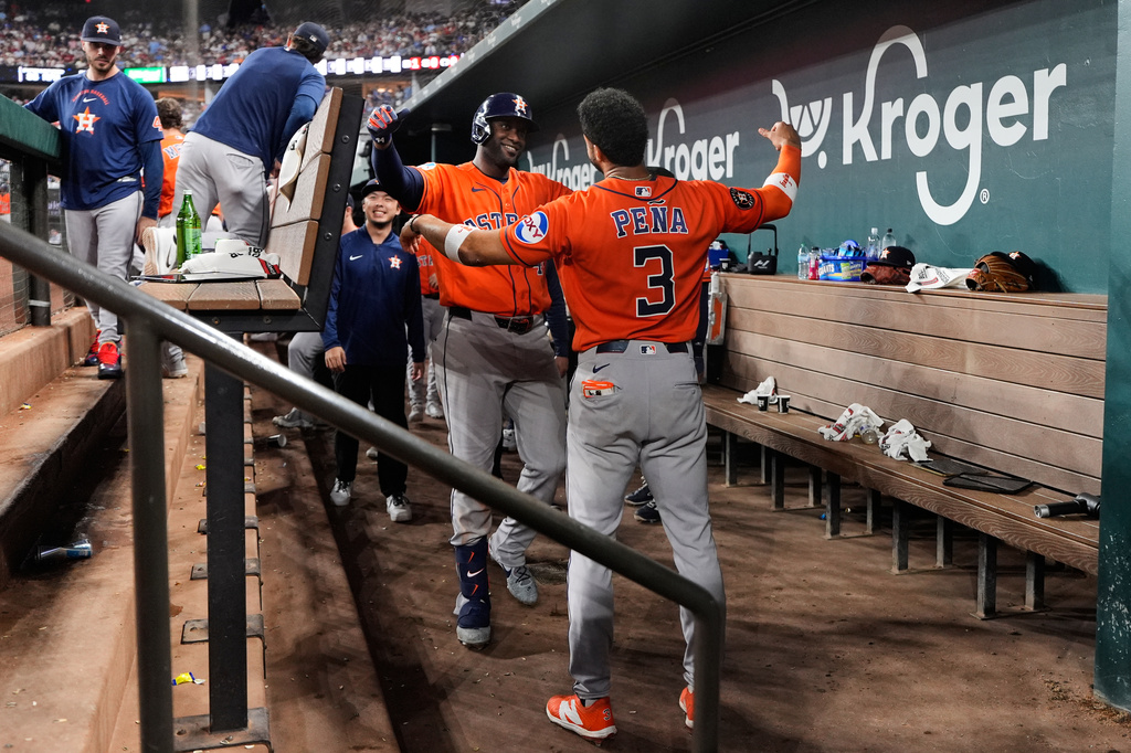 Houston Astros' Yordan Alvarez, left, and Jeremy Pena (3) celebrate in the dugout after Alvarez hit a solo home run in the eighth inning of a baseball game against the Texas Rangers Wednesday, May 27, 2026, in Arlington, Texas. (AP Photo/Tony Gutierrez)