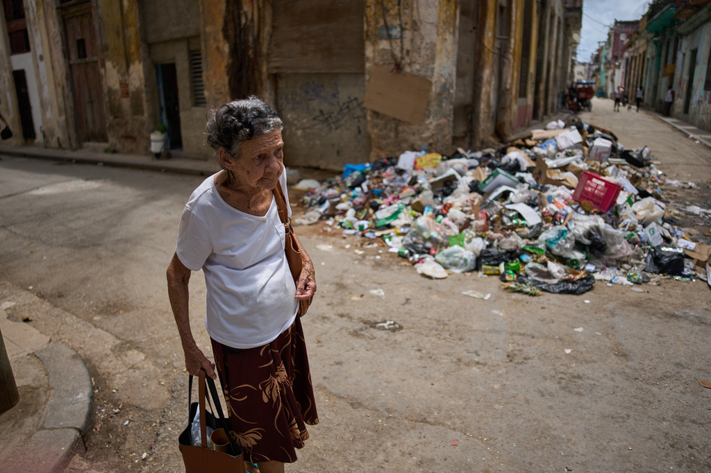 Mercedes Lopez Rey, 83, walks past uncollected trash on her way to her one-room apartment in Old Havana, Cuba, Friday, April 10, 2026. (AP Photo/Ramon Espinosa)