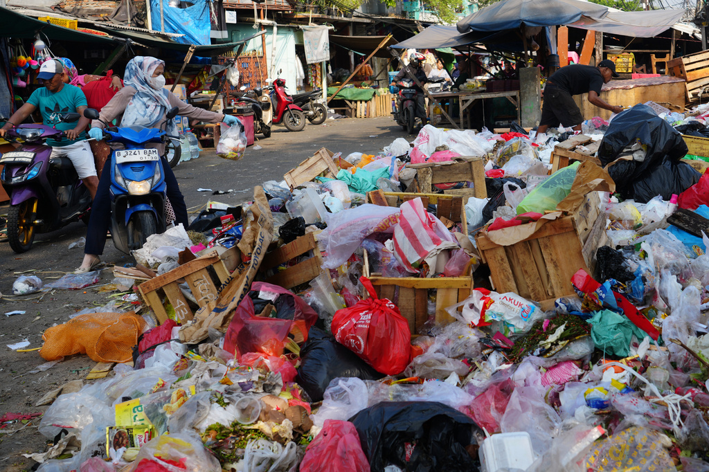 A woman throws a bag of trash onto an open garbage dump in Jakarta, Indonesia, Friday, July 17, 2026. (AP Photo/Tatan Syuflana)