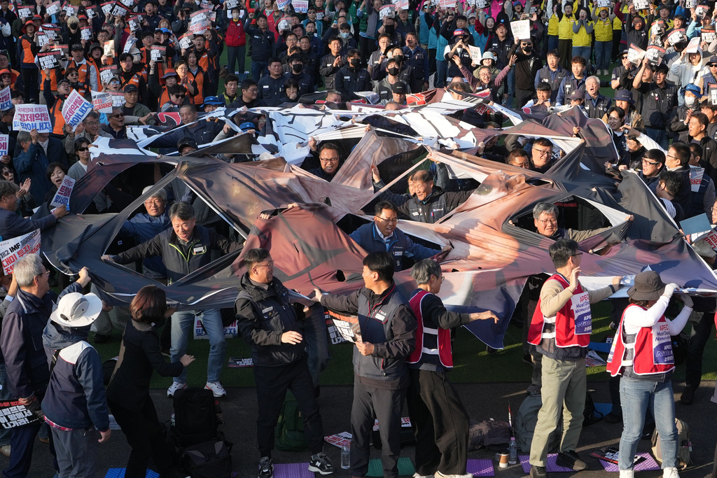 Protesters tear a banner with a face image of U.S. President Donald Trump during a rally in Gyeongju, South Korea, Wednesday, Oct. 29, 2025. (AP Photo/Lee Jin-man)