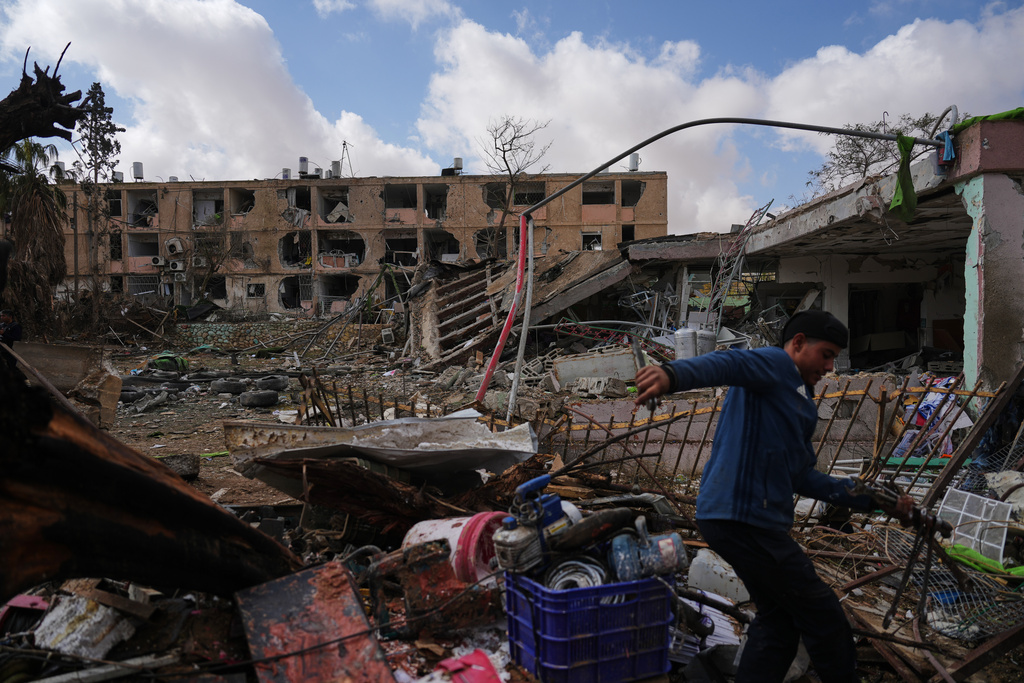 People survey a site that was struck by an Iranian missile in Dimona, southern Israel, Sunday, March 22, 2026. (AP Photo/Ariel Schalit)