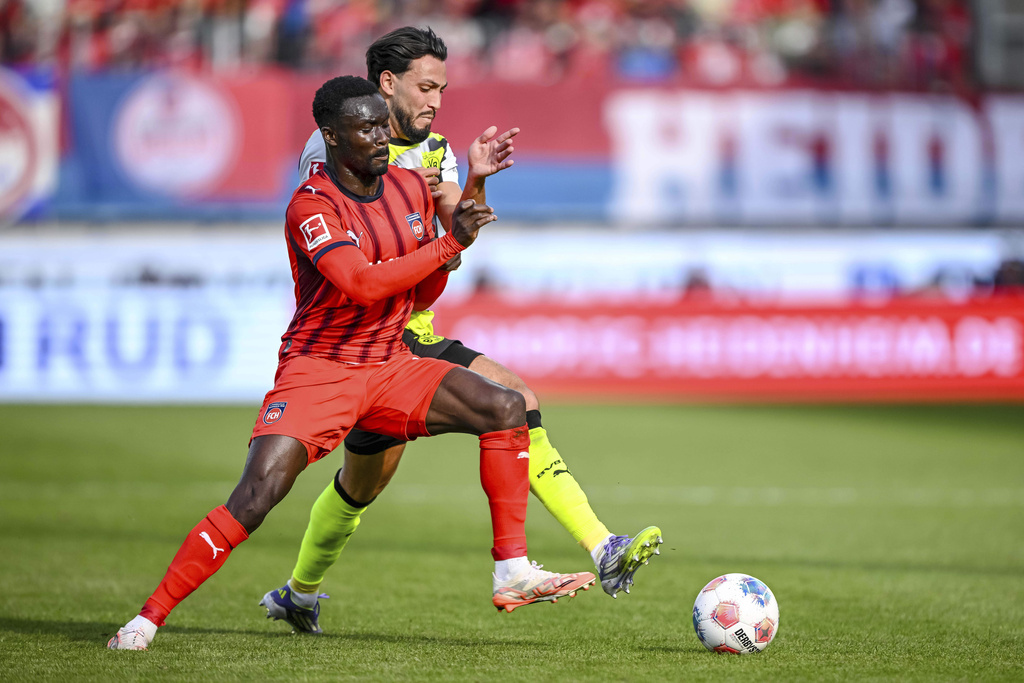Dortmund's Ramy Bensebaini, right, and Heidenheim's Sirlord Conteh, left, challenge for the ball during the German Bundesliga soccer match between 1. FC Heidenheim and Borussia Dortmund in Heidenheim, Germany, Saturday, Sept. 13, 2025. (Harry Langer/dpa via AP)