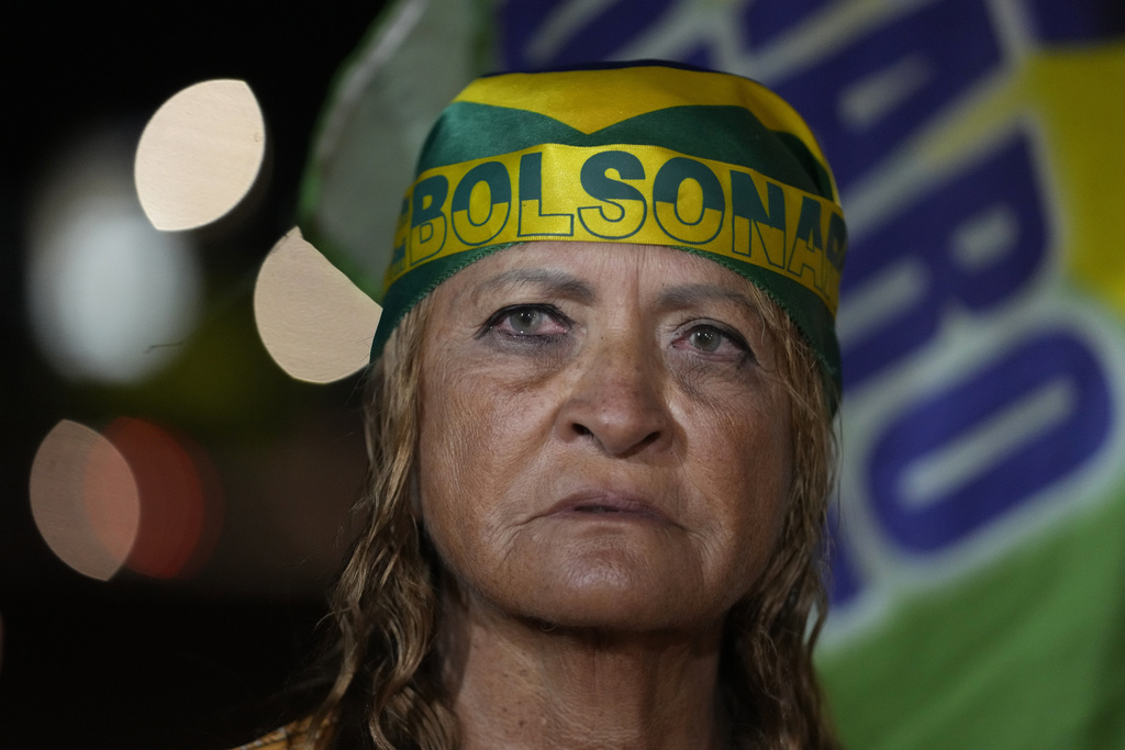 A supporter of former President Jair Bolsonaro prays during a vigil in his support near his home where he is under house arrest, in Brasília, Brazil, Tuesday, Sept. 9, 2025. (AP Photo/Eraldo Peres)
