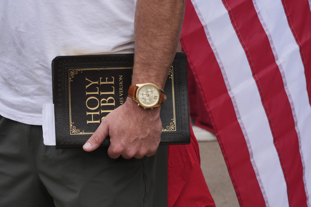 A man holds a Bible outside before a memorial for conservative activist Charlie Kirk, Sunday, Sept. 21, 2025, at State Farm Stadium in Glendale, Ariz. (AP Photo/Jae C. Hong)