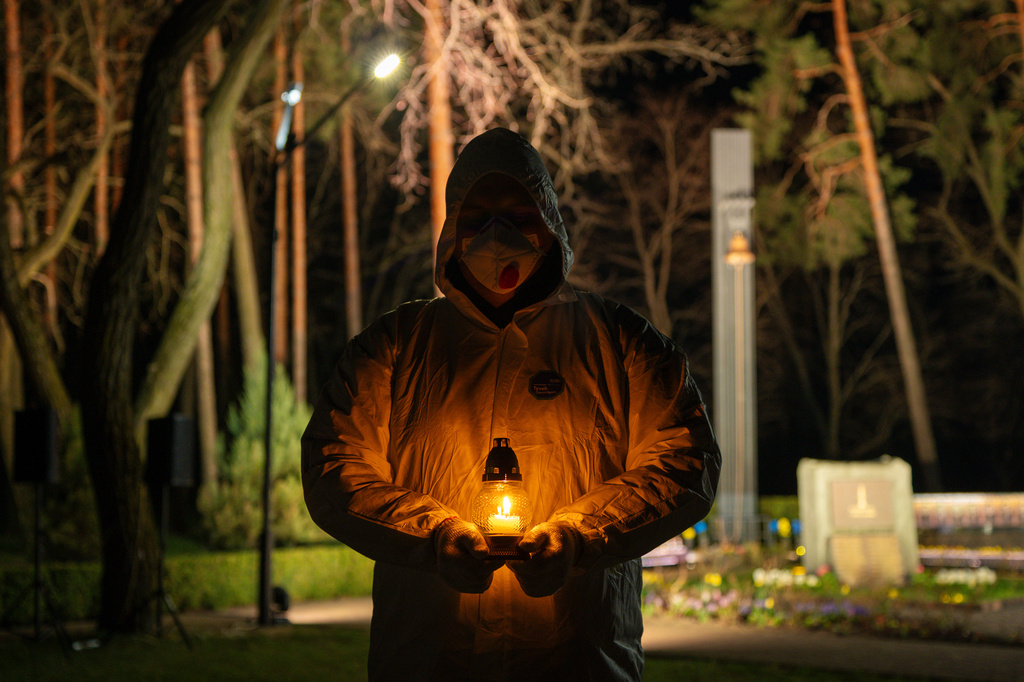 A man dressed in white protective suits holds a candle during a memorial service dedicated to firefighters and workers who died after the 1986 Chornobyl (Chernobyl) nuclear disaster, ahead of its 40th anniversary in Slavutych, Ukraine, Saturday, April 25, 2026.Chornobyl is the Ukrainian name for the city. (AP Photo/Dan Bashakov)
