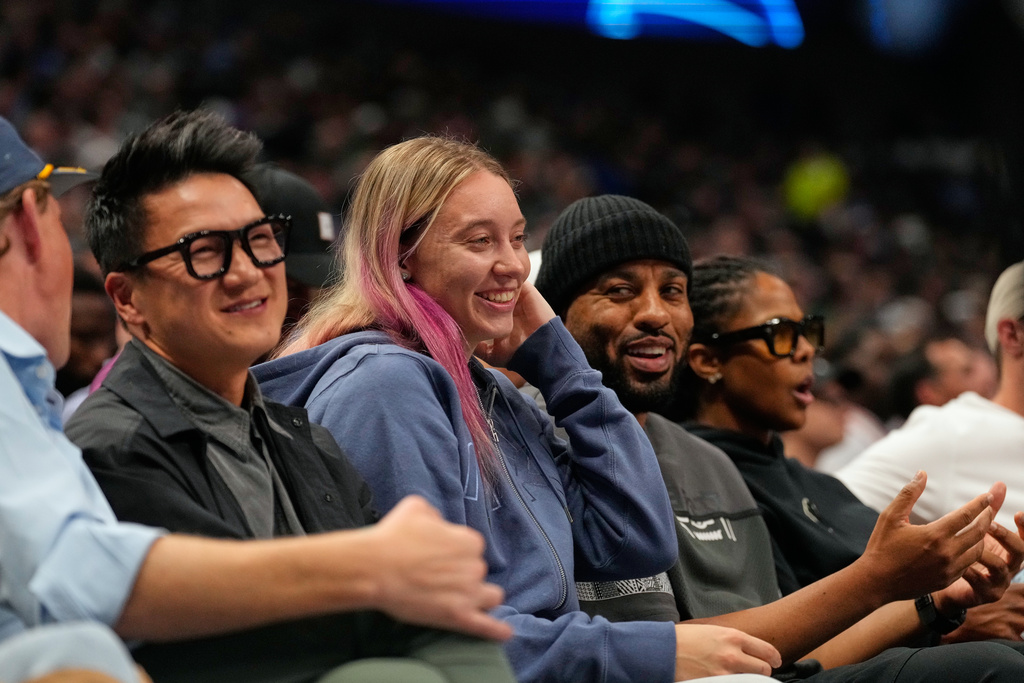 WNBA player Dallas Wings Paige Bueckers, center, sits court side in the first half of an NBA basketball game between the New York Knicks and Dallas Mavericks Wednesday, Nov. 19, 2025, in Dallas. (AP Photo/Tony Gutierrez)