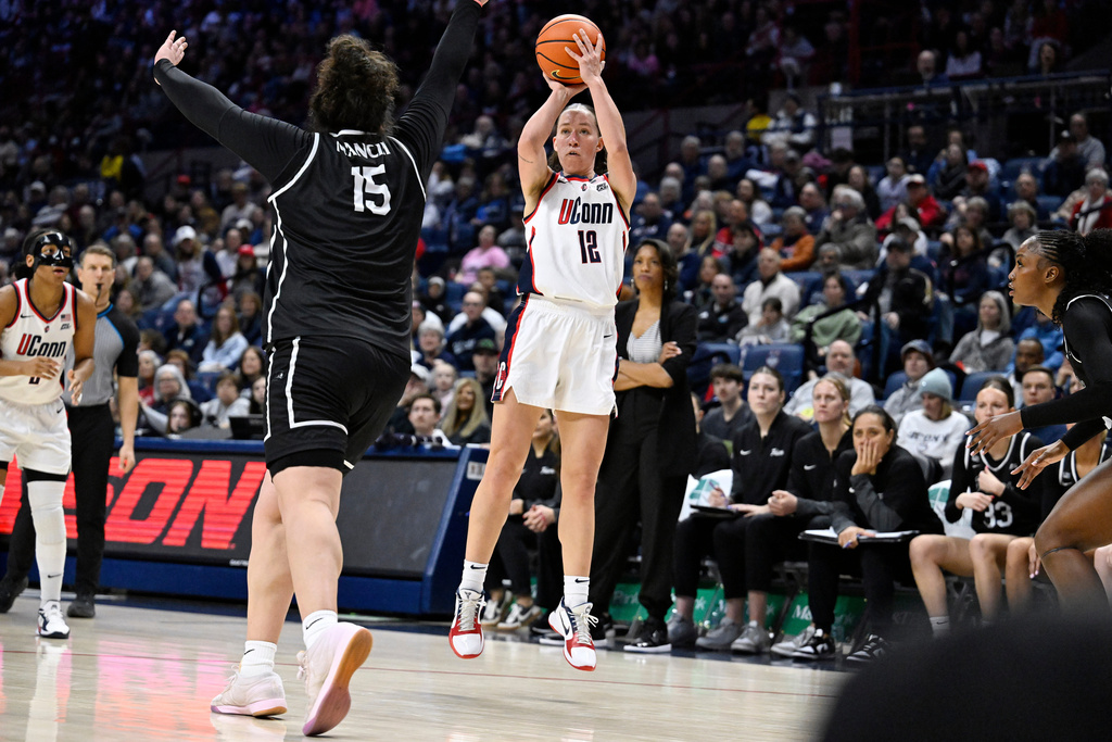 UConn guard Ashlynn Shade (12) shoots as Providence forward Sami Mancini (15) defends in the first half of an NCAA college basketball game, Sunday, Feb. 22, 2026, in Storrs, Conn. (AP Photo/Jessica Hill)