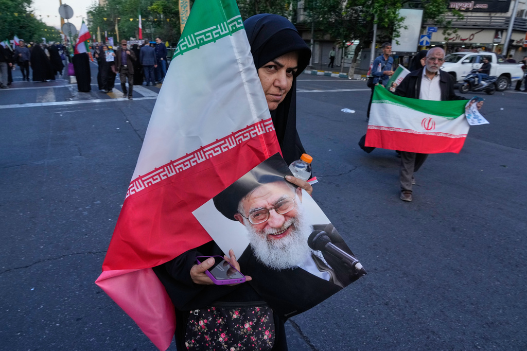 A woman carries an Iranian flag and a poster of the late Supreme Leader Ayatollah Ali Khamenei during a state-organised rally in Tehran, Iran, Wednesday, April 29, 2026, celebrating the birthday of Imam Reza, the 8th Shiite Muslims' Imam, and supporting Supreme Leader Ayatollah Mojtaba Khamenei. (AP Photo/Vahid Salemi)